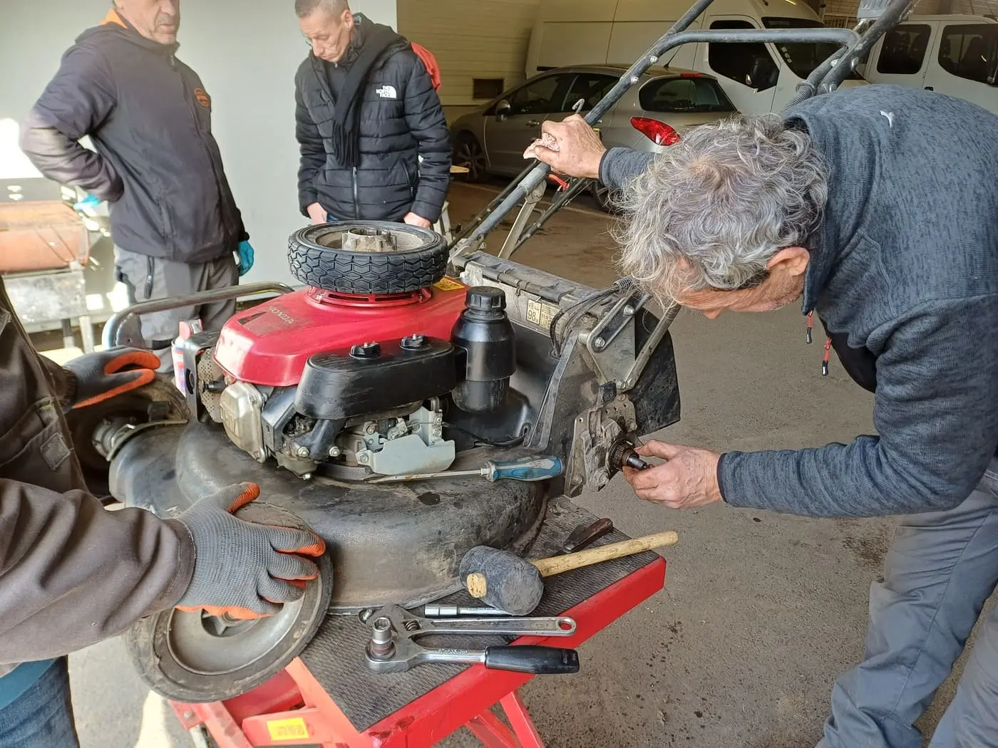 Apprenant démontant une roue de tondeuse pour diagnostiquer une panne lors d'une formation en mécanique.